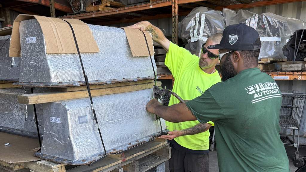 Pekerja di tempat pembongkaran mobil Everett Auto Parts sedang mengikat dua baterai Chevy Volt di atas palet kayu untuk dikirim ke fasilitas daur ulang.